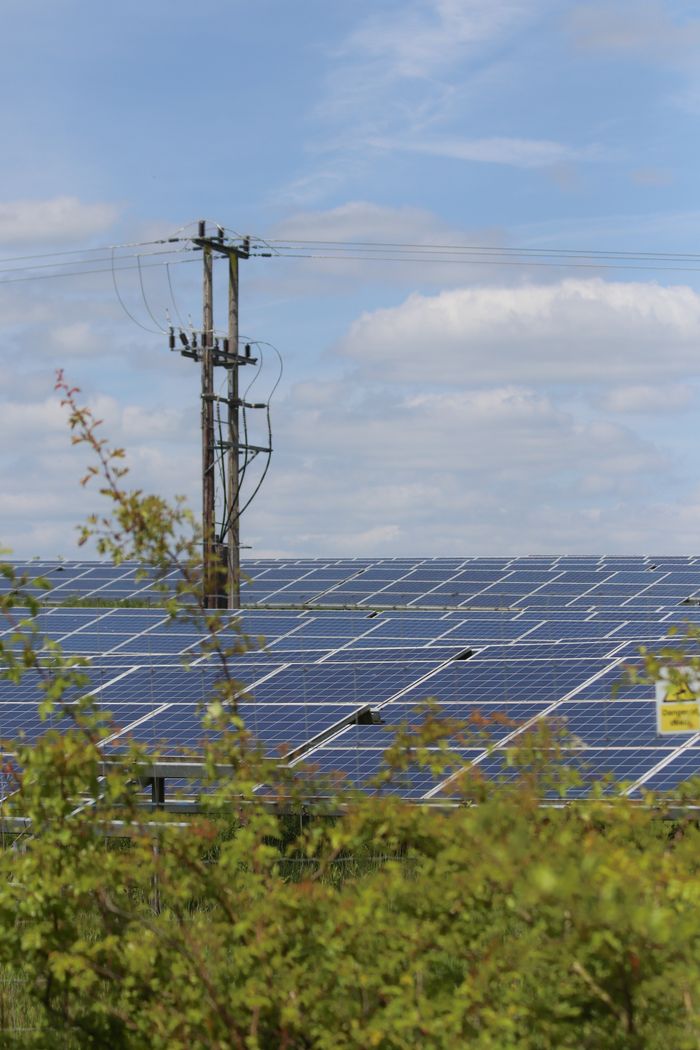 gallery-01 Solar panels in a rural area with power lines, illustrating renewable energy integration.