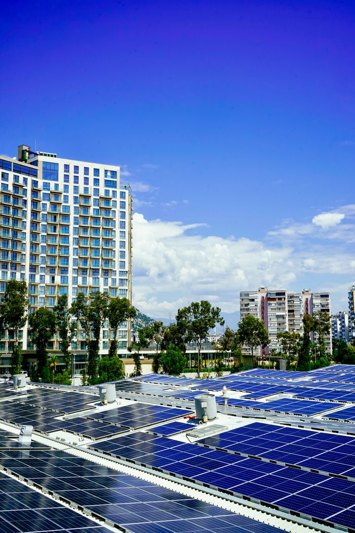 our-services-03 High-rise buildings and a large solar panel array under a clear blue sky.